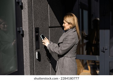 Smart home concept - close up of woman use mobile phone to open electronic lock