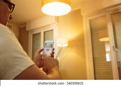 Smart Home: Man Controlling Lights With App On His Phone