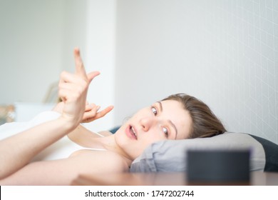 Smart Home Plays Fan Music Through A Portable Speaker. Young Woman In Bed Is Dancing Against The Background Of A Smart Speaker