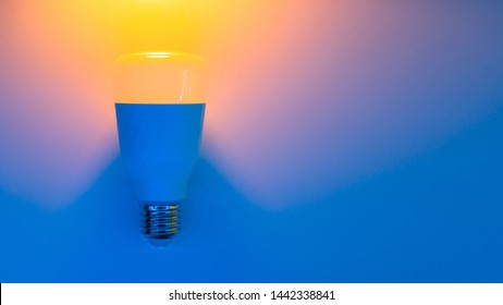 Smart Home RGB Bulb Lamp In Trendy Neon Backlight. LED Smart Bulb, Multicolor Backdrop. Top View, Copy Space For Your Design, Classic Blue Concept