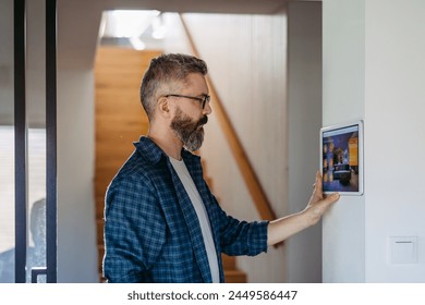 Smart home system. Man adjusting household functions, lighting, security cameras, door locks and smart thermostat or heating settings. Concept of sustainable and smart technology at home. - Powered by Shutterstock