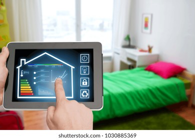 smart home and technology concept - close up of male hands pointing finger to tablet pc computer with house settings on screen over kids room background - Shutterstock ID 1030885369