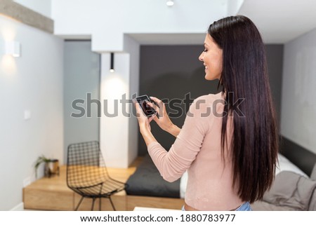 Smart home technology interface on smart controler app screen with augmented reality AR view of internet of things IOT connected objects in the apartment interior, person holding device