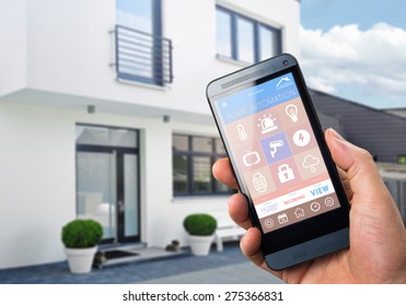 Smart House, Home Automation, Device With App Icons. Man Uses His Smartphone With Smarthome Security App To Unlock The Door Of His House.