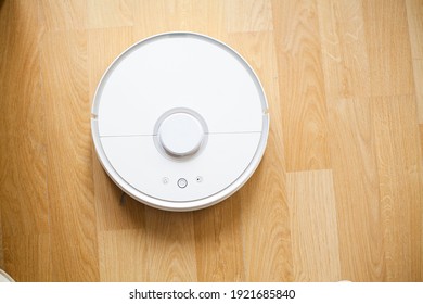 Smart House. Vacuum Cleaner Robot Runs On Wood Floor In A Office