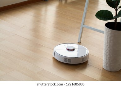 Smart House. Vacuum Cleaner Robot Runs On Wood Floor In A Office