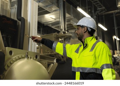 Smart HVAC system engineer with green safety jacket and PPE hold digital tablet and and walkie talkie working at site line of HVAC control room HVAC machinery
