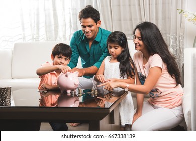 Smart Indian/asian Couple Teaching Importance Of Saving To Kids At Home With Piggy Bank