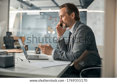 Smart intelligent specialist sitting at the office table and giving recommendation to client
