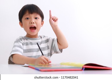 Smart Little Asian Boy Having An Idea While Doing His Homework, Isolated On White Background