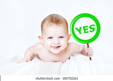 Smart little boy holding a sign "Yes" in the hands. Photo in light background.