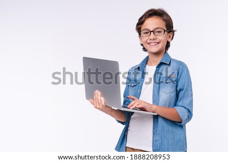 Smart little boy with laptop in casual clothes isolated over white background
