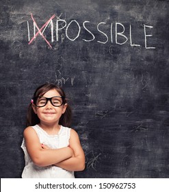 Smart Little Girl Smiling In Front Of A Blackboard