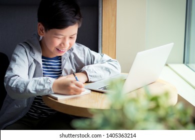 Smart looking Asian boy happily and cheerfully studying online lessons with his computer laptop. Researching, writing and solving problem with concentration. Online learning and self study concept.  - Shutterstock ID 1405363214