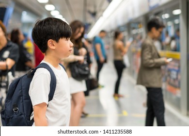 Smart Looking, Confident Asian Preteen Boy Wear White T-shirt, Backpack, Wait For Underground Train In Crowded Platform In The Morning, Routine Commute Of School Student, City Lifestyle, Life Skills. 