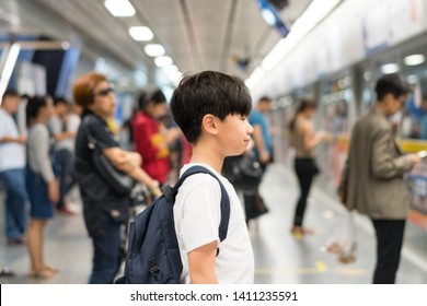 Smart Looking, Confident Asian Preteen Boy Wear White T-shirt, Backpack, Wait For Underground Train In Crowded Platform In The Morning, Routine Commute Of School Student, City Lifestyle, Life Skills. 