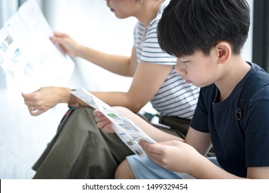 Smart Looking Preteen Asian Boy Reading City Map Or Tourism Information Brochure While Traveling With Family In Other Country. Tourist, Exploring, Life Skills, Jouney, Travel Plan, On The Go. Arrival.