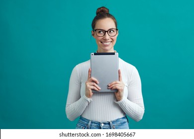 Smart Looking Student And Business Woman With Glasses, Smiling Looking To The Copy Space At Left, While Holding A Tablet, Isolated On Green Color Background