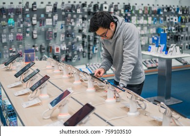 Smart Male Customer Choosing Smartphone In The Mobile Phone Shop. Difficult Decision. Various Choice. He Is Smiling