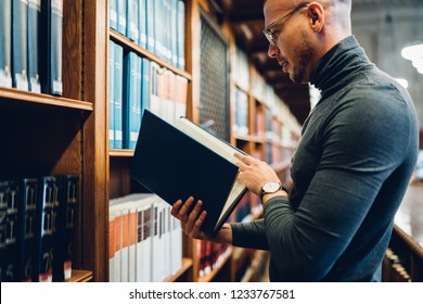 Smart Male Journalist Concentrated On Scientific Research Working With Literature In Archive, Clever Young Professor Reading Book In Public Library Using Books Information For Intellectual Project 