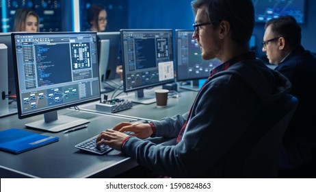 Smart Male IT Programer Working On Desktop Green Mock-up Screen Computer In Data Center System Control Room. Team Of Young Professionals Programming Sophisticated Code