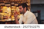 Smart man in white shirt drinking cocktail Old fashioned of special party beverage vibrant waiting for friends or couple at nightclub on Friday meeting night time at luxurious counter bar. Vinosity.