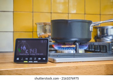 Smart meter placed next to gas stove with blue flames burning - Shutterstock ID 2161076975