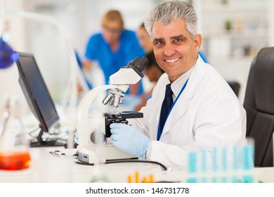 smart middle aged scientist using microscope in the lab