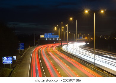 Smart motorway in England, UK with light trails signifying busy traffic at rush hour. The NSL symbols under the gantry sign signify an end to speed restrictions.
