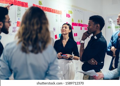 Smart Multiethnic Male And Female Coworkers In Formal Clothing Setting Goals With Colorful Sticky Notes And Discussing At Creative Office 