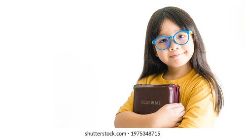 smart and nerd asian kid girl wearing eye glasses holding Bible for study in church.school kid.Online learning.Read book.examination at home.Self esteem proud.Christian catholic child kid.history.