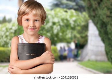 Smart And Nerd Kid Girl Holding Bible For Study In Church.