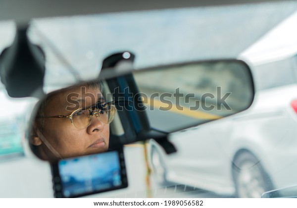 Smart older woman driving car with video\
recorder drive view mirror on highway, dash cam digital for safety\
road in traffic accident, Cam front windshield record traffic ahead\
and navigation