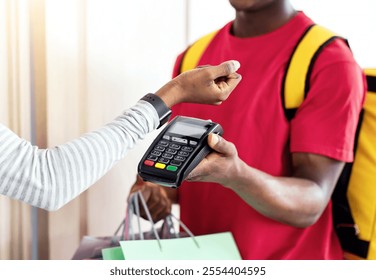 Smart Payment For Delivery. African American Female Paying Courier Guy Putting Smartwatch To Terminal Receiving Shopping Bags Standing At Doors Of Her Home. Cropped, Selective Focus - Powered by Shutterstock