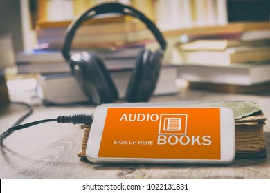 Smart phone with audio books application on screen, headphones and the paper books. Concept of listening to audiobooks.
