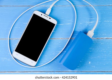 Smart Phone And Backup Battery On The Blue Wooden Background