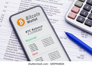 Smart Phone With Bitcoin Wallet On Bank Statement With Calculator And Pen.