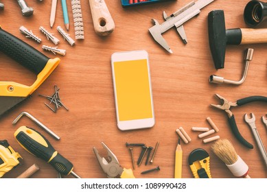 Smart Phone With Blank Screen On Repairman Workdesk. Copy Space For Text Or Handyman Maintenance Work Mobile Phone Application Or Business Service App, Top View