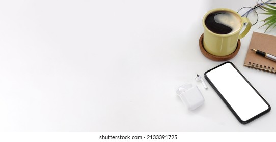 Smart phone, coffee cup, notebook and wireless earphone on white table. Top view, copy space. - Powered by Shutterstock