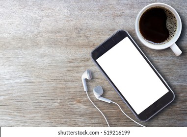 Smart Phone And Earphone With Cup Of Coffee On Old Wooden Background With Copy Space. Top View