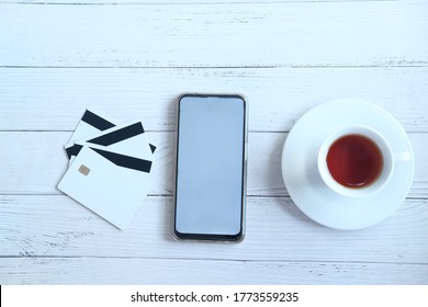 Smart Phone With Empty Screen , Credit Card And Tea On Table 