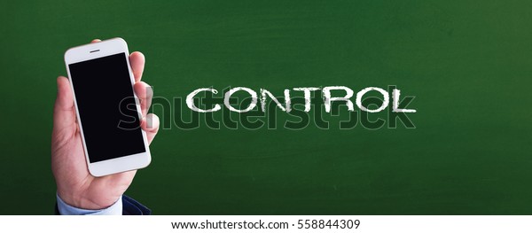 Smart phone in hand front of blackboard and\
written CONTROL