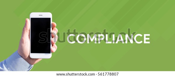 Smart phone in hand front of green background\
and written COMPLIANCE