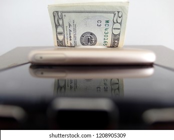 Smart phone and money, cash in dollars and mobile phone -  concept of online business / profitable e-commerce / make more income from technology.