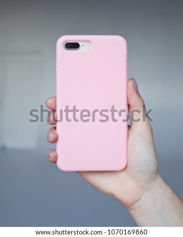 Smart phone on a gray background in a pink plastic case back view. Smartphone in a woman's hand. Template of phone case