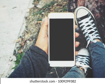 Smart phone on hand with sneakers