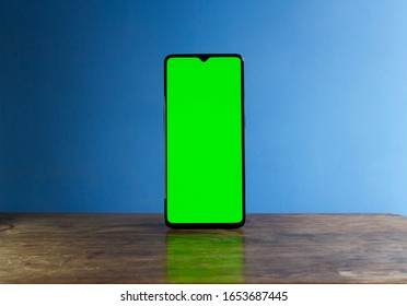 A Smart Phone On Its Own, Stood Up In Portrait Orientation. It Has A Blank, Green Screen Display, For Mock-ups Like Showing App Development, Or To Use In A Graphic Design. Cell Phone Is Isolated.