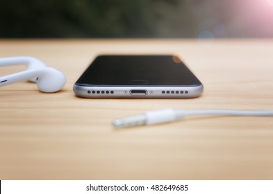 Smart phone on the table without audio connectors. No Headphone jacks nor microphone jacks 3.5 mm. Stereo speakers. Shallow depth of field.  