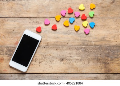 Smart Phone On Wooden Table With Heart Background With Copy Space