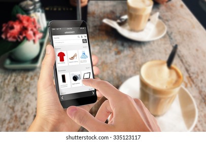 Smart phone online shopping in man hand. Desk with caffe in background. Buy clothes shoes accessories with e commerce web site